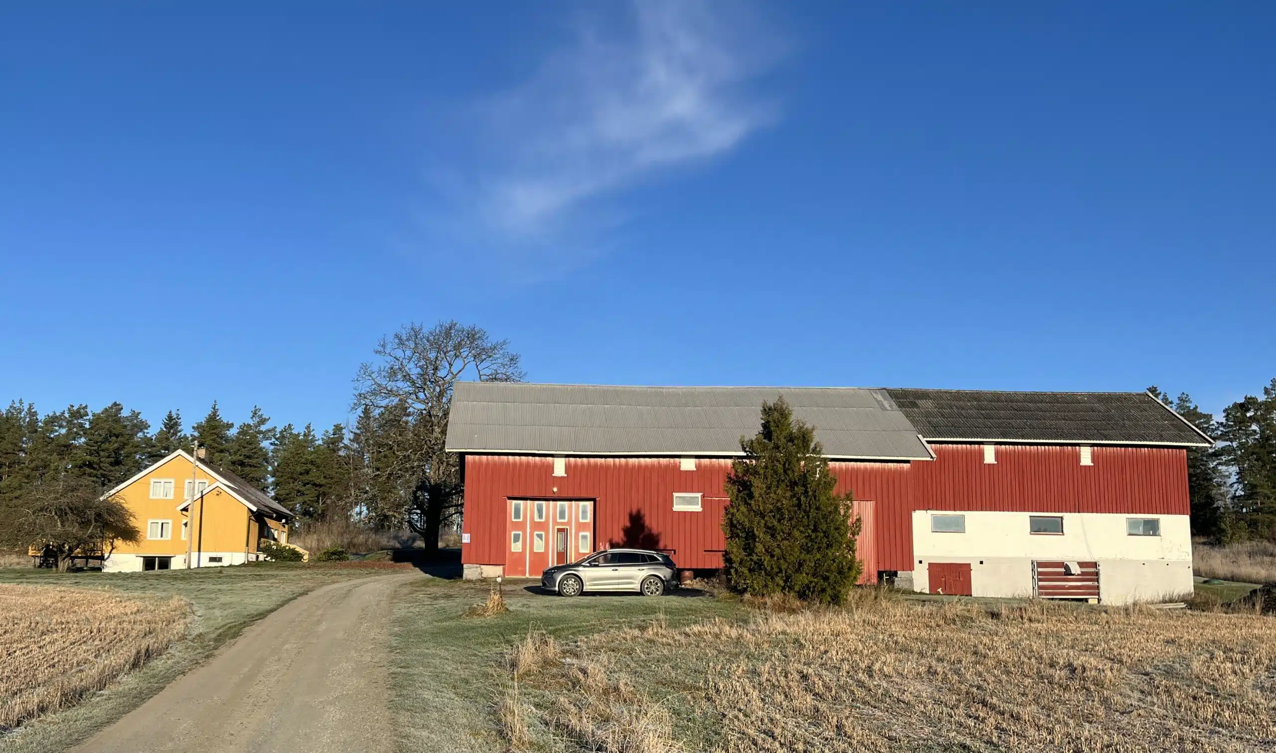Gårdsbygg med bil foran